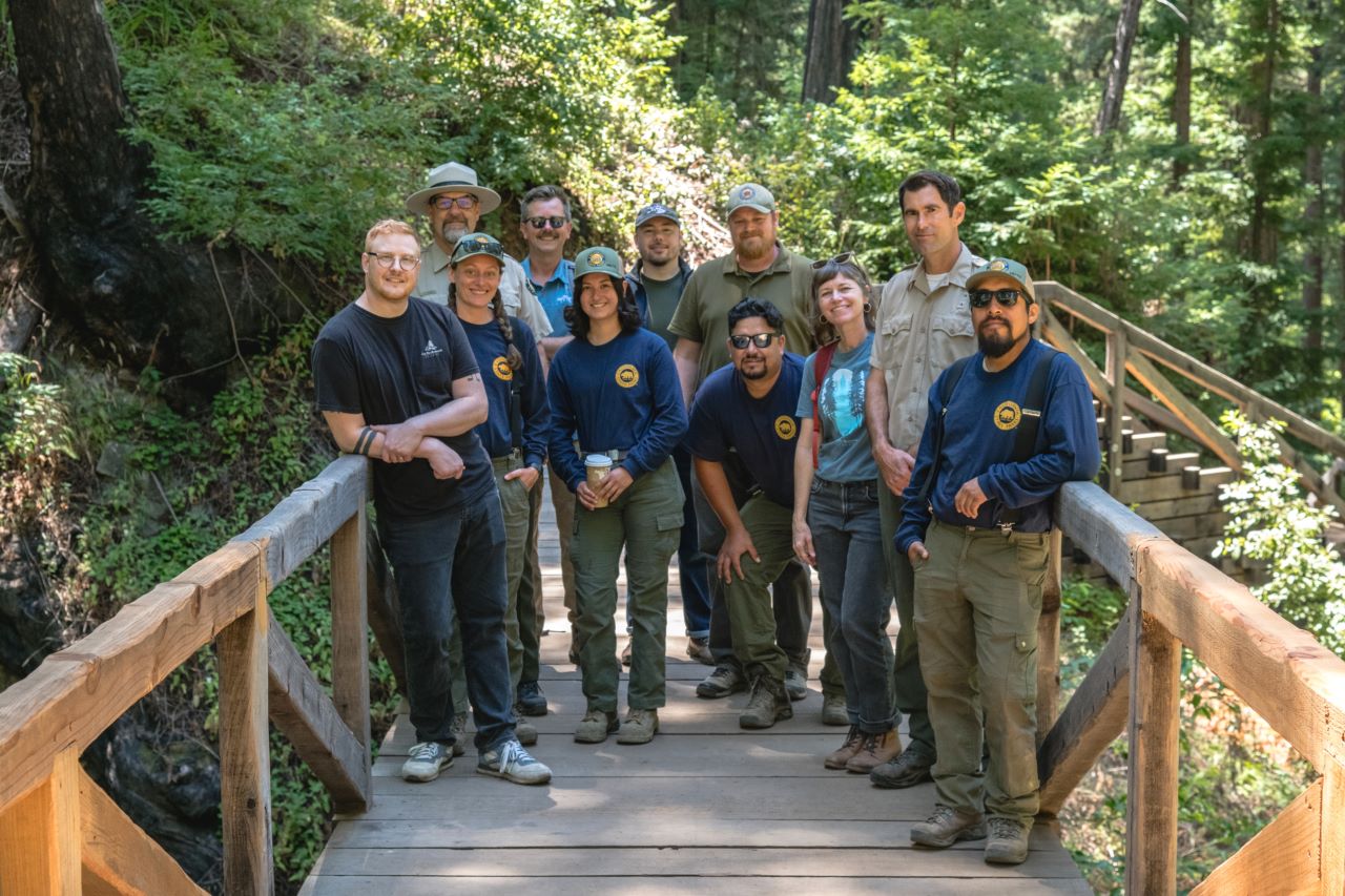 Members of California State Parks and Save the Redwoods League staff on the repaired pedestrian bridge of the recently reopened Pfeiffer Falls Trail. Photo from Lisa Morales Winner, courtesy of Save the Redwoods League